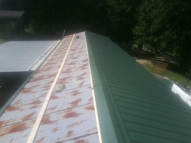 Old rusted panels beside newly installed green metal roofing — Wind Damage Roof Repair by Roofing Brothers in Ibapah