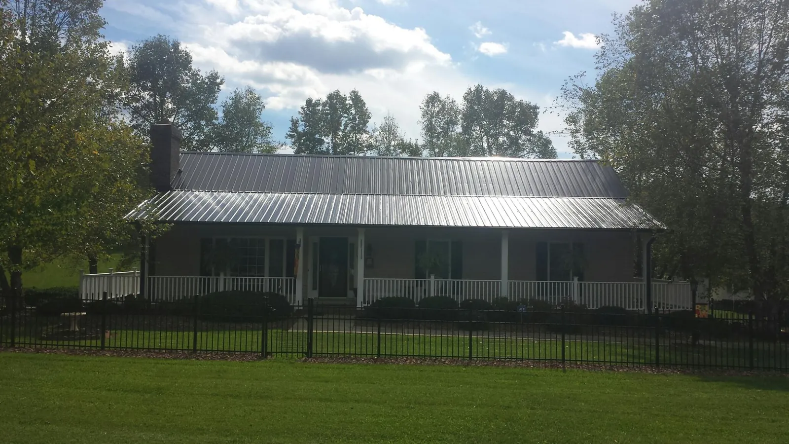 Gray metal roof on a brick ranch with a full width front porch — Gutter Guard Installation work by our crew in Ibapah