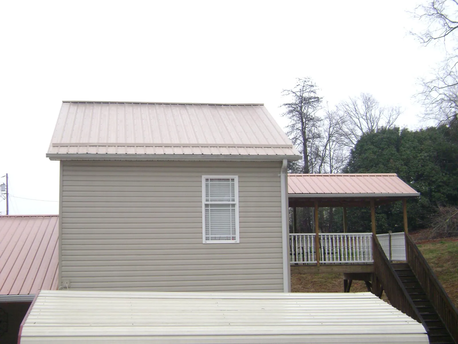Tan metal roofs on a two story addition and attached porch, from a Roof Replacement job in Ibapah