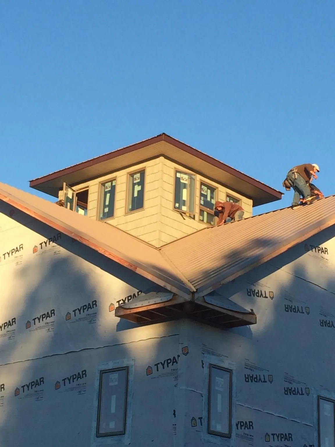Roofers working around a rooftop cupola on a new metal roof at sunset — Roof Waterproofing in Ibapah by Roofing Brothers